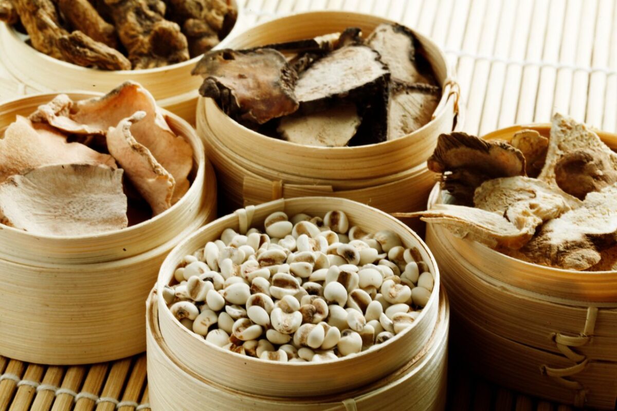 about-04 From above many wooden containers filled with assorted dried mushrooms with condiments and raw cashew nuts placed on bamboo mat