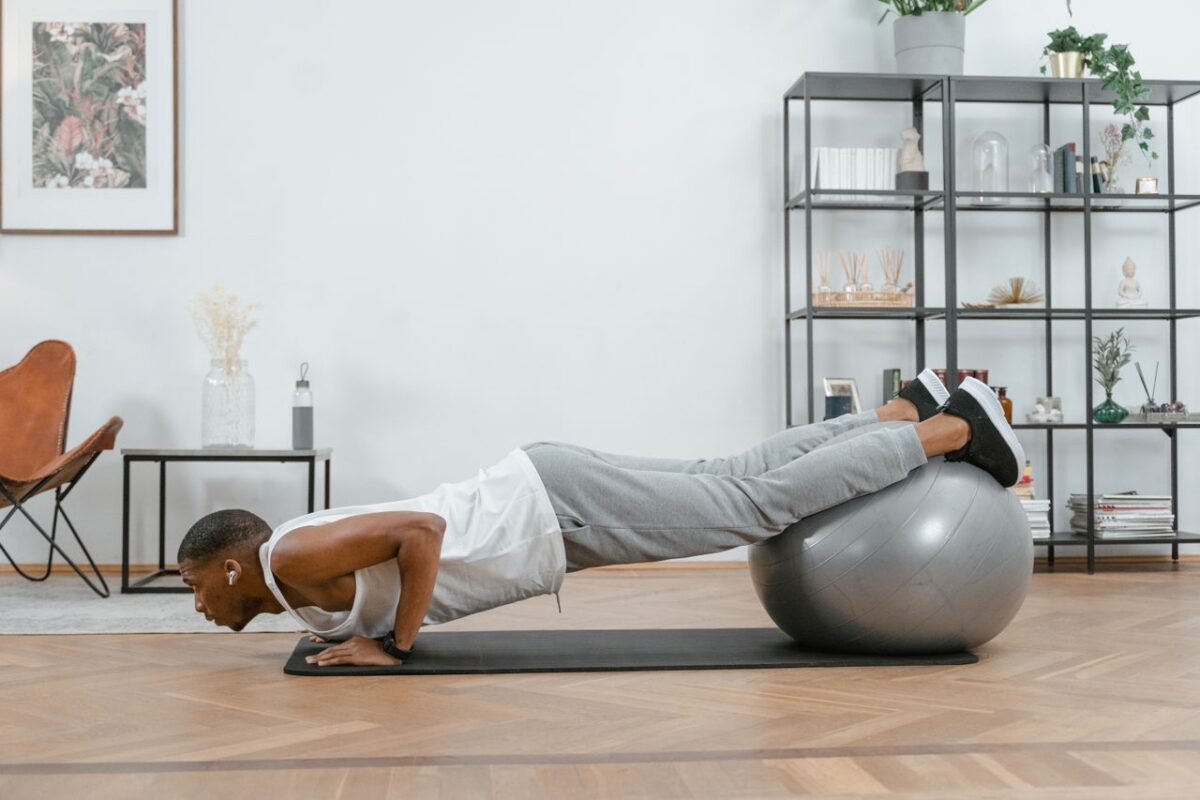 services-04 Adult doing push-ups with an exercise ball indoors for fitness and health.